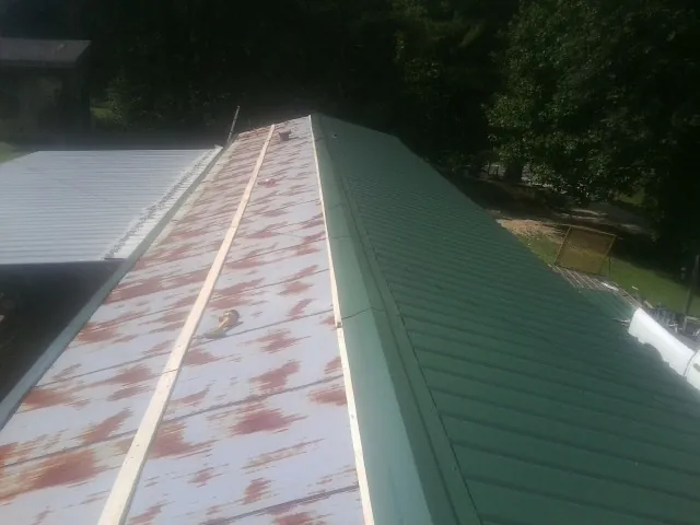 Old rusted panels beside newly installed green metal roofing — Wind Damage Roof Repair by Roofing Brothers in Brookfield